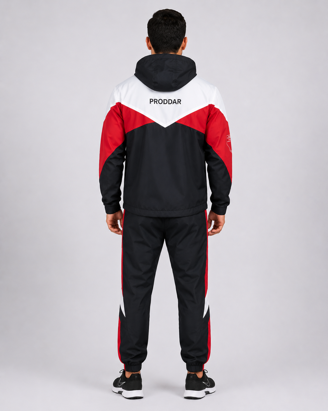 Parte posterior del buzo deportivo institucional con chaqueta de capucha y pantalón deportivo de diseño tricolor, vista posterior.