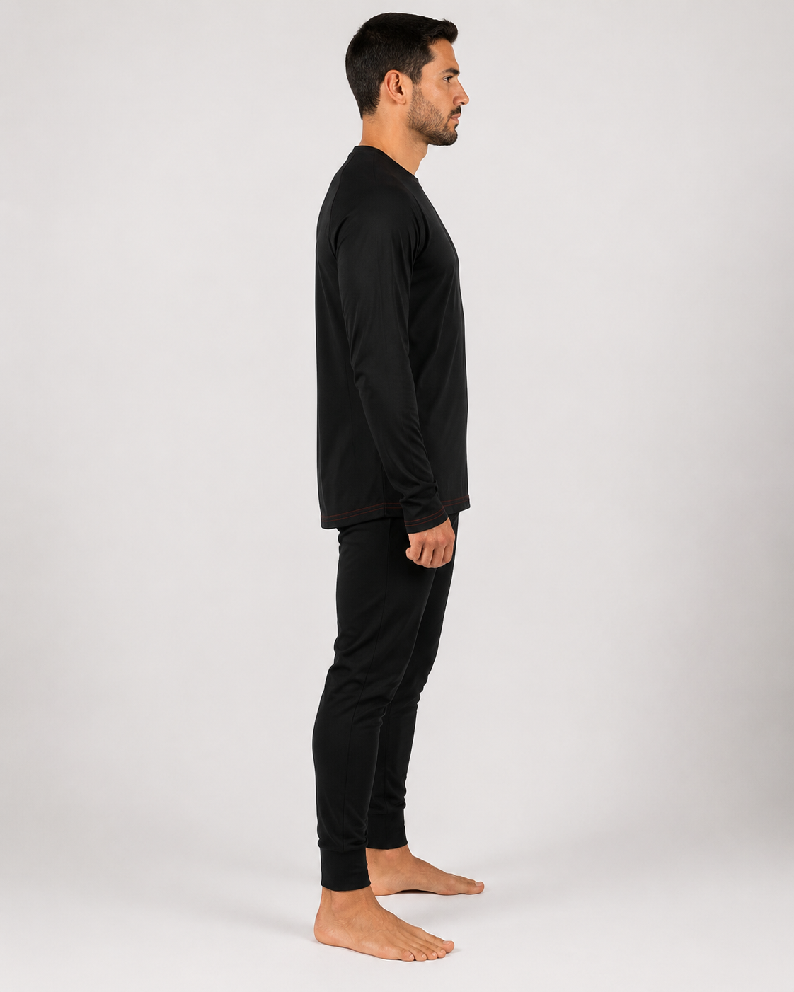 Primera capa ignífuga certificada con camiseta de manga larga y pantalón negro de ajuste anatómico, vista lateral izquierda.