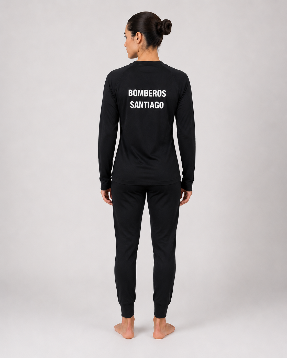 Primera capa ignífuga femenina con estampado identificatorio en la espalda y pantalón negro de ajuste anatómico, vista posterior.