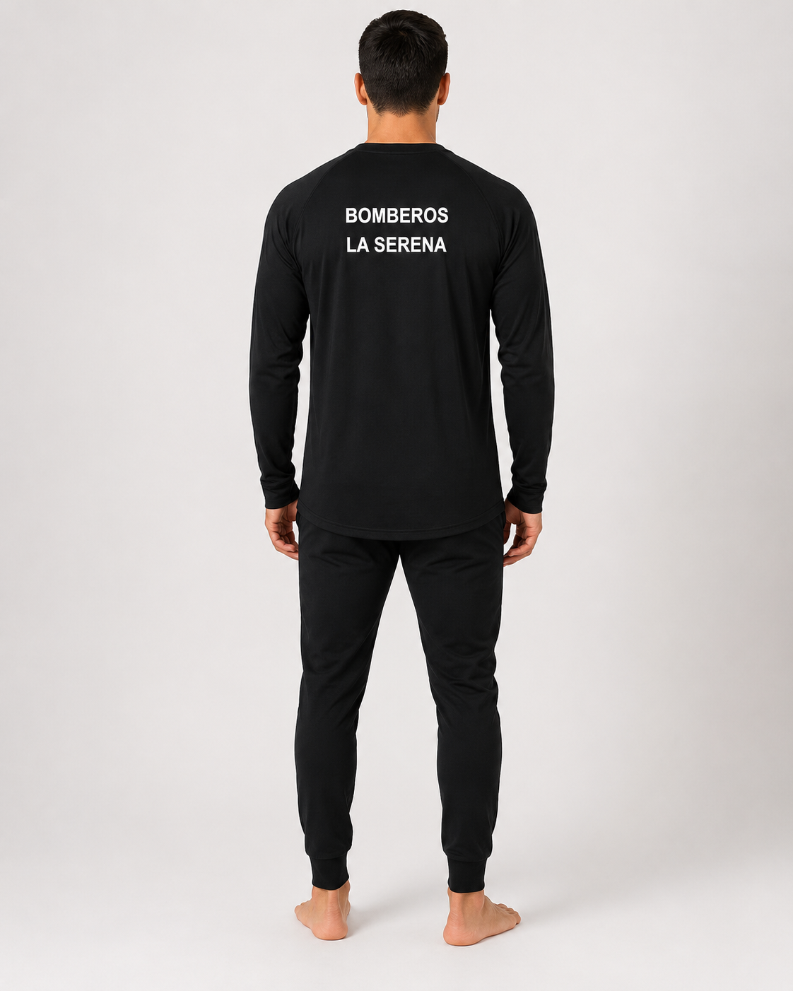 Primera capa ignífuga certificada con estampado identificatorio en la espalda y pantalón negro de ajuste anatómico, vista posterior.