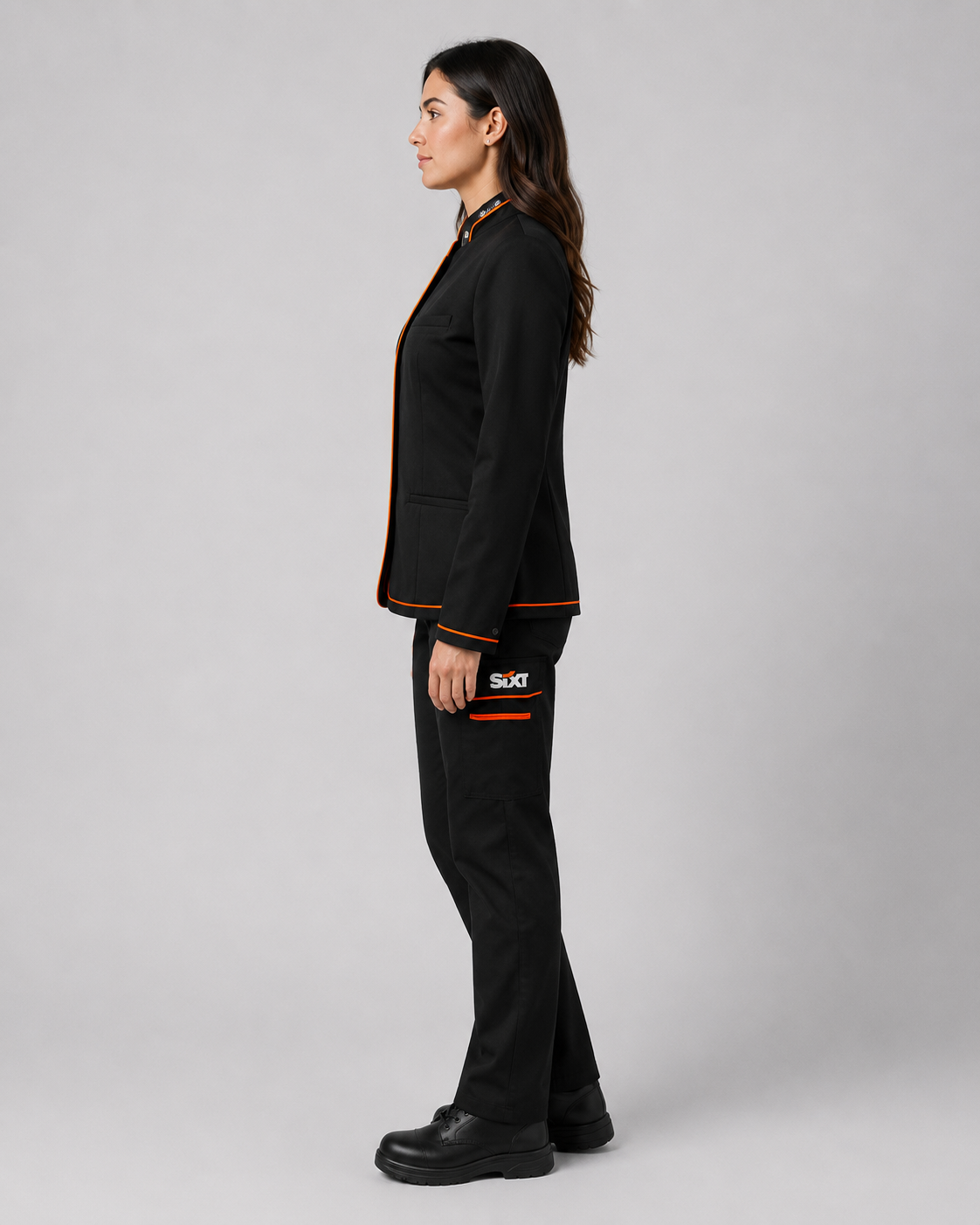 Uniforme ejecutivo femenino compuesto por chaqueta de botones y pantalón cargo negro con detalles naranjas, vista tres cuartos.