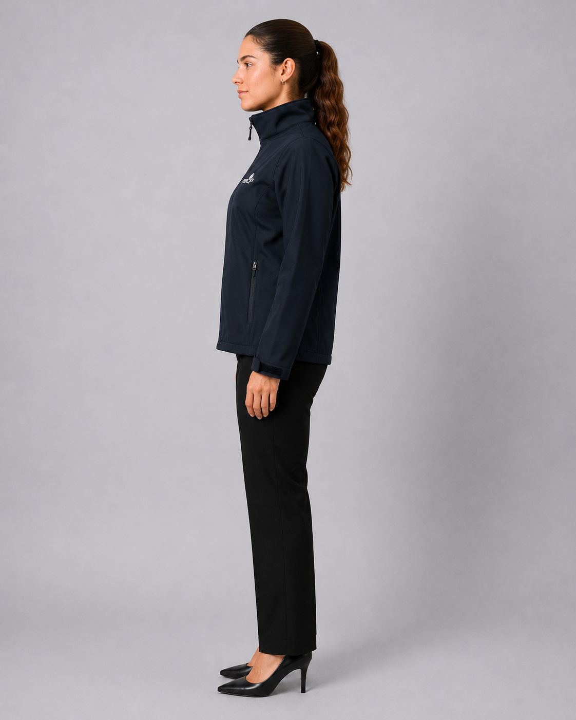 Uniforme corporativo femenino compuesto por chaqueta Softshell con bolsillos laterales y pantalón negro, vista lateral derecha.