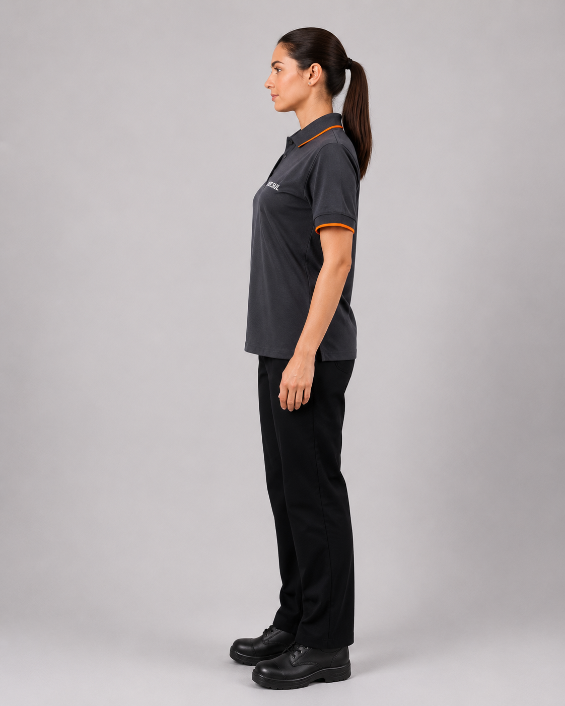 Uniforme operativo femenino con polera polo gris de manga corta, detalles naranjos y pantalón negro, vista lateral izquierda.