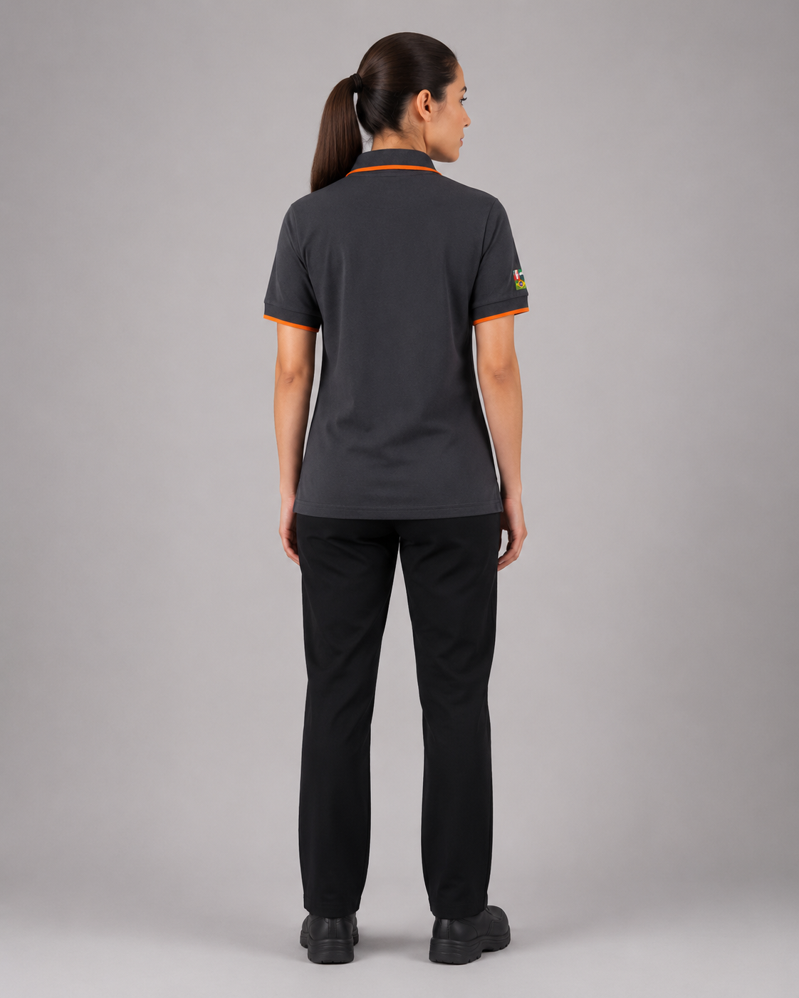 Parte posterior del uniforme operativo femenino con polera polo gris y pantalón negro, vista posterior