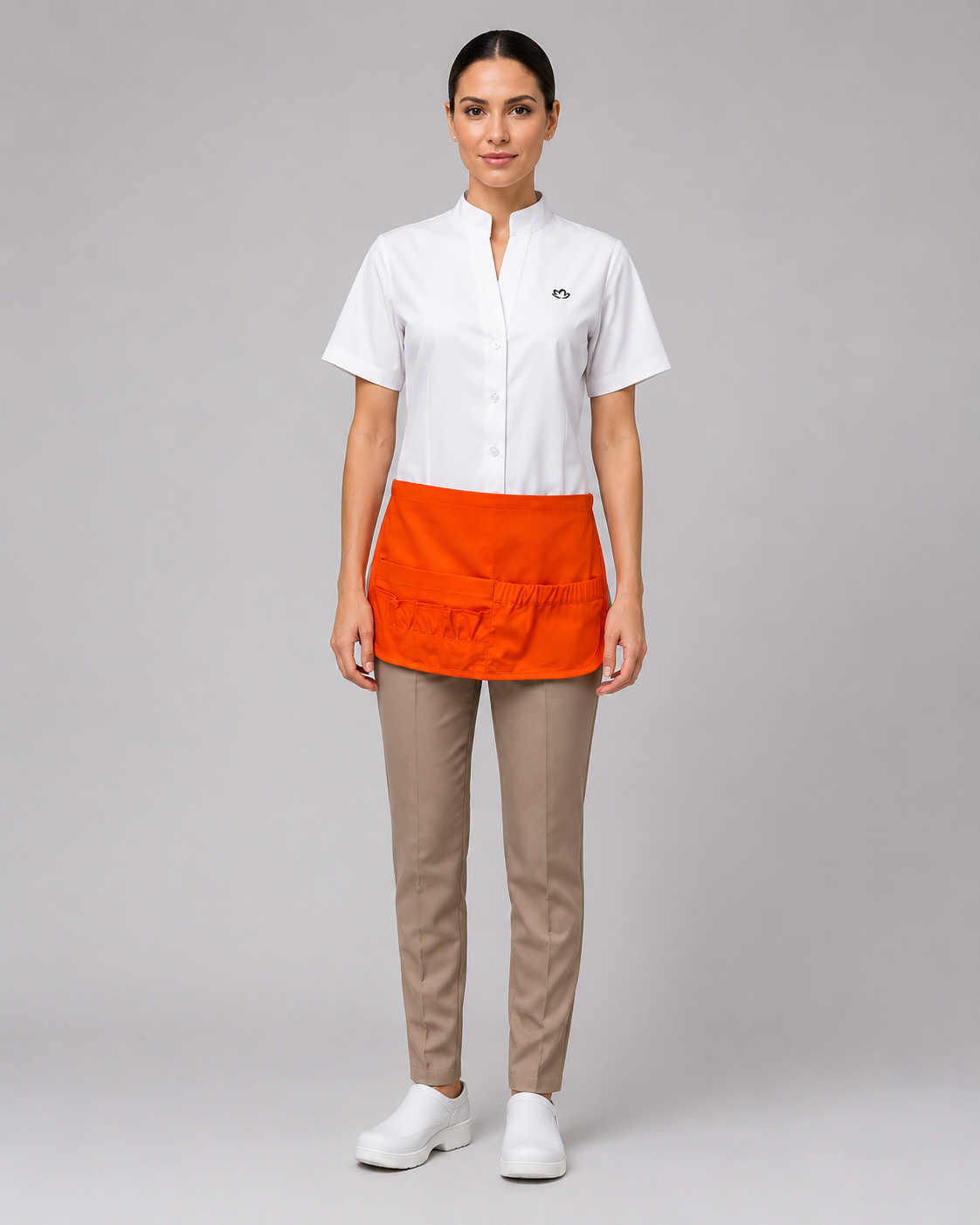 Uniforme corporativo para atención en retail con blusa blanca de manga corta, pantalón beige y delantal de gabardina color naranja, vista frontal.