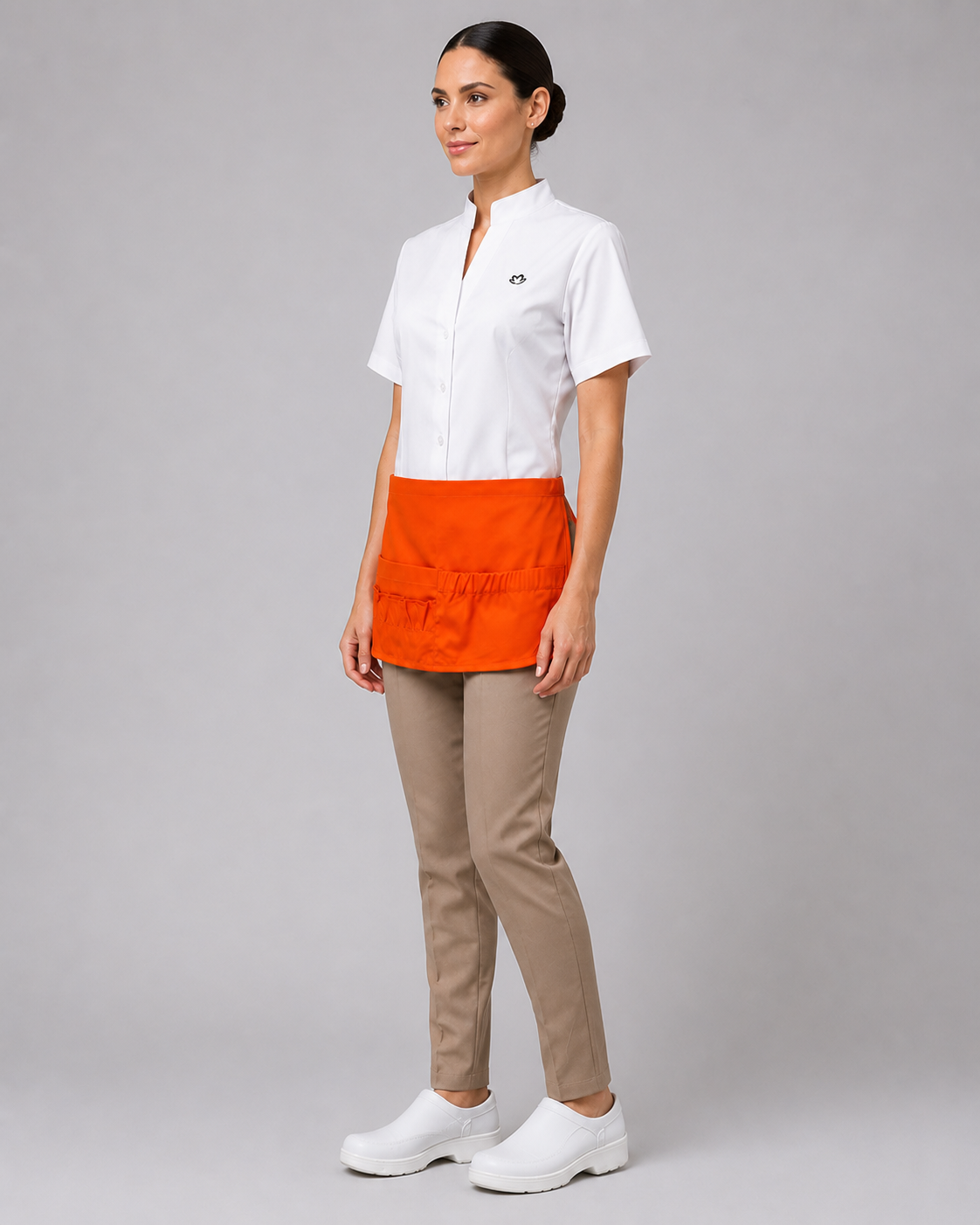 Uniforme profesional con blusa de cuello mao, pantalón recto beige y delantal de gabardina con bolsillos organizadores, vista lateral izquierda.