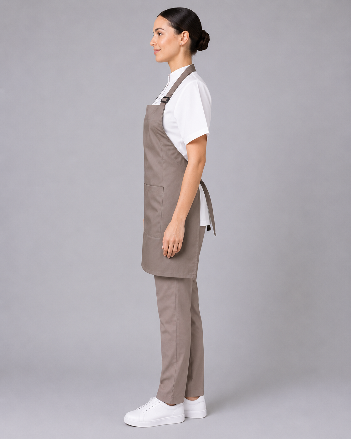 Uniforme para atención al cliente con pechera de gabardina ajustable, blusa blanca de manga corta y pantalón beige, vista lateral izquierda.