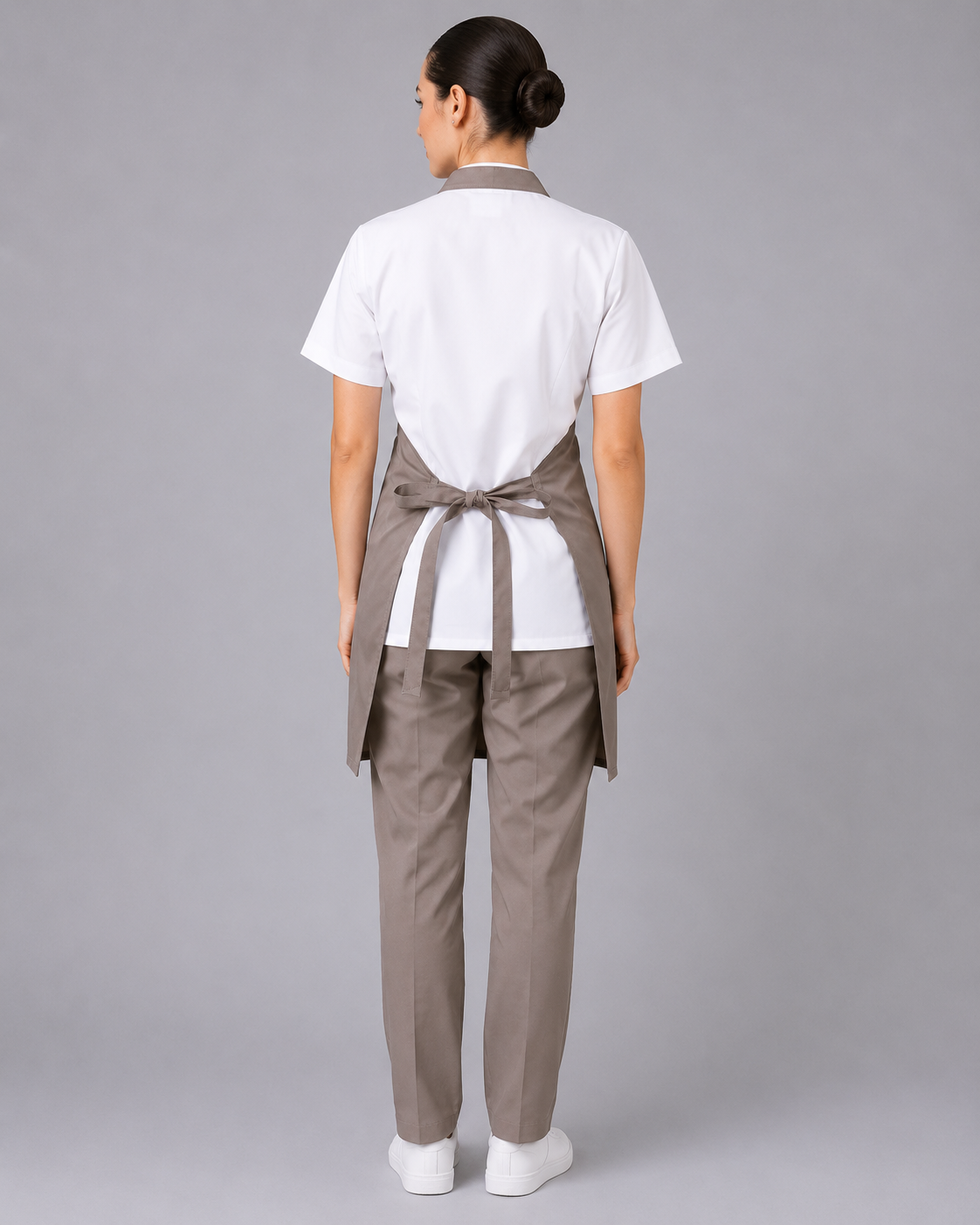 Parte posterior del uniforme corporativo con blusa blanca, pantalón beige y pechera ajustable mediante amarras posteriores, vista posterior.
